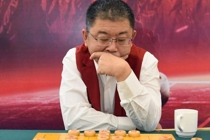Li Laiqun resting his chin on his hand at the board